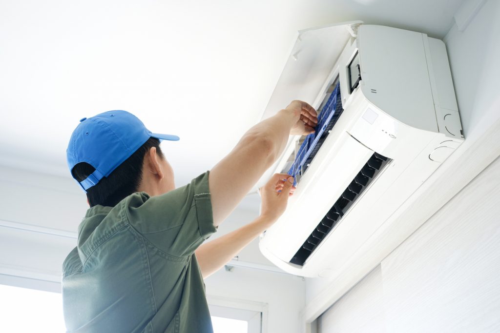 Male repair air conditioner at room, He is air technician , mechanic , engineer. Maintenance air conditioner myself.