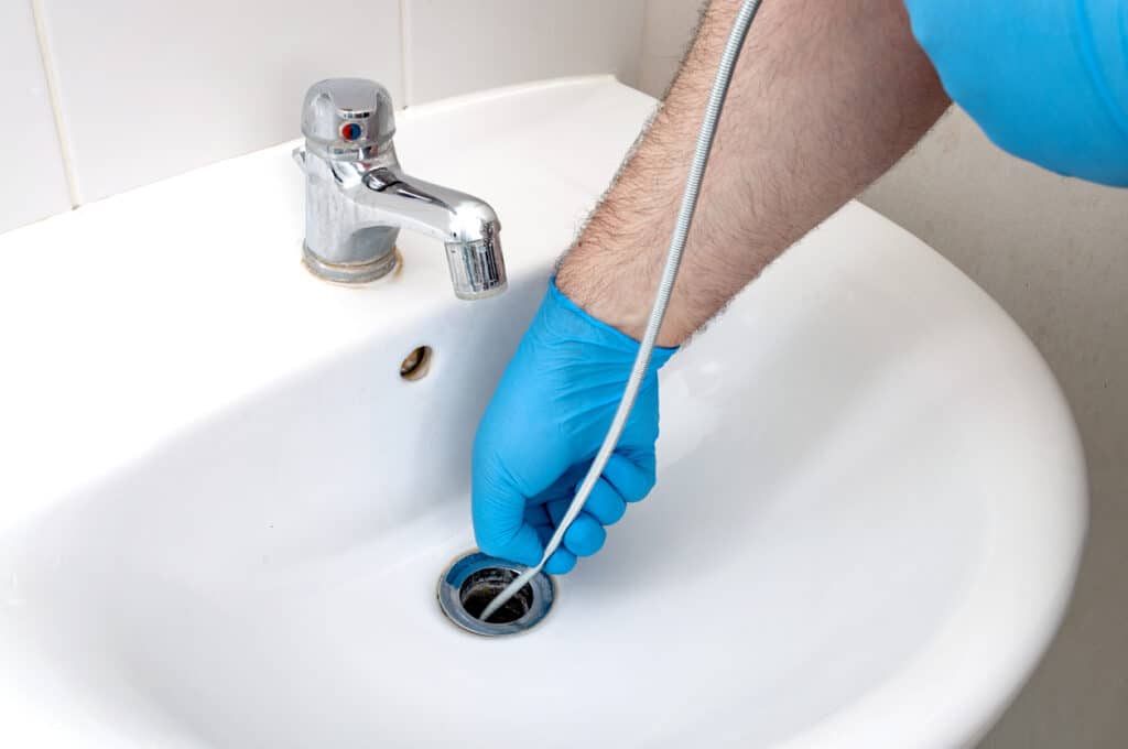 Plumber repairing drain with plumbers snake